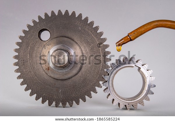 Lubricate metal gears with gear oil. Spare\
parts used in car workshops. Light\
background.