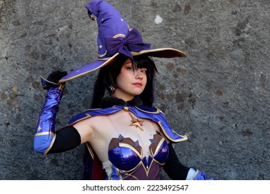 Lucca, Tuscany, Italy - October 29, 2022: Cosplayer Girl Dressed As Mona, Character From The Fantasy Video Game Genshin Impact At The Lucca Comics And Games 2022 Cosplay Event.