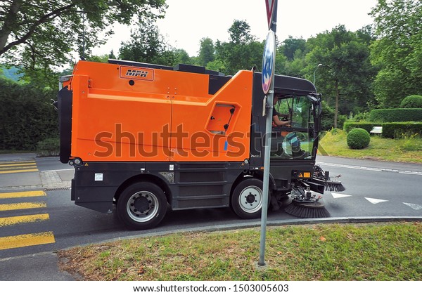 Lucerne\
Switzerland - 25 June 2018: red road sweeper cleaning car truck\
driving on the city road in Lucerne\
Switzerland