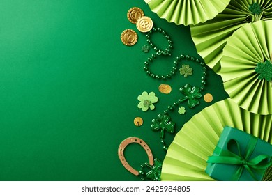 Luck of the irish: festive green and gold. Top view shot of green paper fans, shamrocks, beads, gold coins, horseshoe on green background, perfect for St. Patrick's Day promotions or well-wishes - Powered by Shutterstock