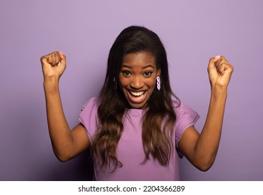 Luck And Success. Happy Black Woman Celebrating Shaking Fists And Gesturing Yes Over Purple Background In Studio.