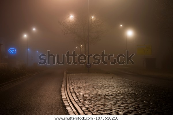 Luckenwalde , Germany , 14.12.2020 , Fog at night\
in the streets of Luckenwalde,Human teaching streets at night in\
the light of street\
lights