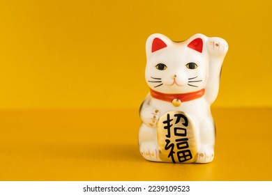 
A lucky cat figurine. In Japan, it is called manekineko. It is written as good luck in Japanese. - Shutterstock ID 2239109523