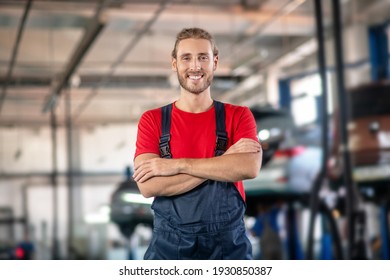 Lucky Day. Smiling Young Adult Man In Work Uniform Posing Standing In Large Car Garage