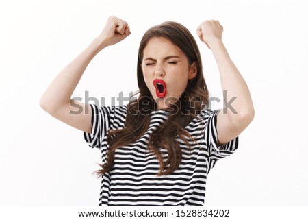 Lucky enthusiastic cheerful young woman win lots money, close eyes happy rejoicing stunning news, fist pump, raise hands excited, yell hooray shout pleased, celebrating victory, achieve success