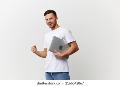 Lucky happy young tanned handsome student man in basic t-shirt raise fist up hold laptop pc posing isolated on over white studio background. Copy space Banner Mockup. Electronics repair concept