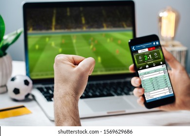 Lucky man celebrating money win  Male fan watching football play online broadcast his laptop  cheering for his favorite team   making bets at bookmaker's website 