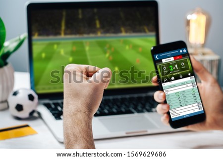 Lucky man celebrating money win. Male fan watching football play online broadcast on his laptop, cheering for his favorite team and making bets at bookmaker's website.