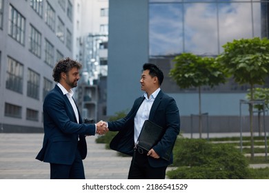 Lucky Multicultural Partners Shaking Hands on Meeting in City. Professional Multiethnic Businesspeople near Office Building, side view. Teamwork Concept 