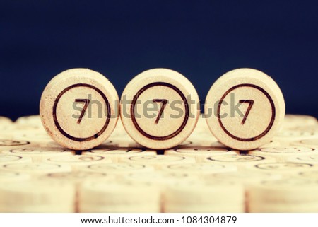 Lucky number 777 on the wooden keg lotto. Black background. Close up