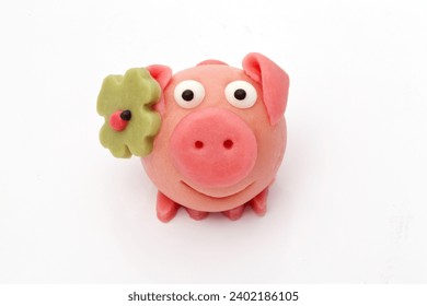 Lucky pig made of marzipan with shamrock and ladybug as a symbol of luck in close-up against a neutral white background