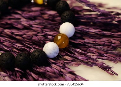 Lucky stone bracelet with agate, quartz, black lava stone on purple dry grain background,popular unisex accessory for who believe in lucky object or amulet help meditation or curing unhappy emotion