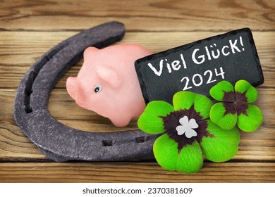 Lucky symbols marzipan piggy and clover with German Good Luck 2024 on wooden background