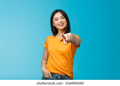 Lucky winner. Cheerful charismatic asian cute urban girl stand yellow t-shirt smiling friendly pointing finger camera choosing, picking person, inviting you team, stand happy blue background - Shutterstock ID 2164904183