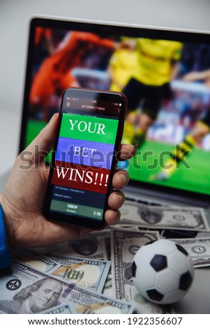 Lucky winner at football betting with phone in hand and dollar bills. Betting concept. Vertical image