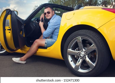 Lucky Young Man Sitting In His New Convertible Car. Low Angle View