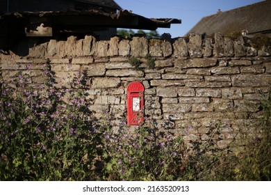 Ludlow,in Shropshire,England,UK. Circa 2017 Red Letter Box Mounted On An Old Brick Wall Down A Country Lane, Surrounded By Wild Plants.Olde England At It's Best !