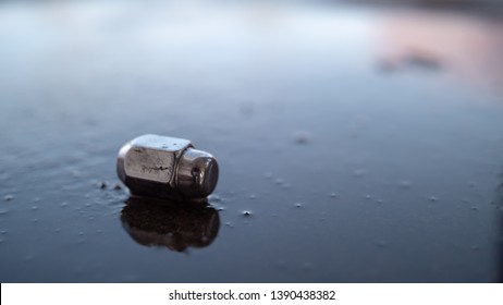 Lug Nut On Wet Pavement Reflecting Sky