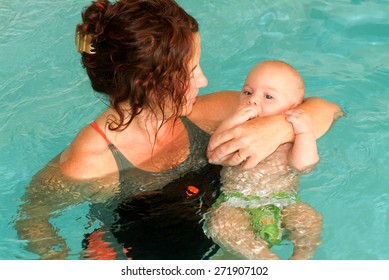 Lugano, Switzerland - 18 October 2007: Adorable baby enjoying swimming in a pool with his mother, early development class for infants teaching children to swim and dive