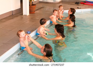 Lugano, Switzerland - 9 February 2005: Adorable babys enjoying swimming in a pool with with their relatives, early development class for infants teaching children to swim and dive
