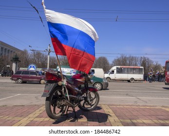 LUGANSK, UKRAINE - MARCH 30, 2014: Bike With A Fixed To It A Russian Flag On The Background Of The Rally.  Lugansk Separatist Rally Gathered Only About 500 People.