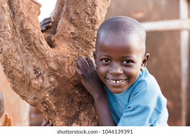 Lugazi, Uganda. 29 May 2017. A Smiling Ugandan Boy Climbing A Tree.