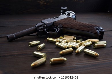 Luger P08 Parabellum handgun and shiny 9 mm bullets on wooden background