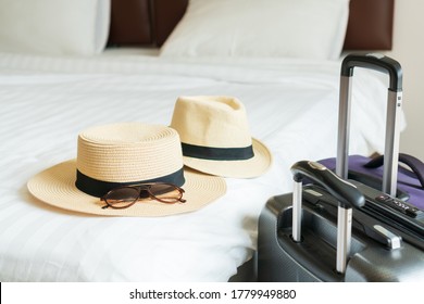 Luggage And Beach Hat Of A Couple On Bed In Modern Hotel Room With Windows, Curtains. Travel, Relaxation, Journey, Trip And Vacation Concepts. Closeup