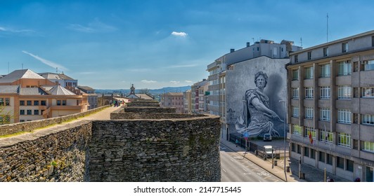 Lugo, Spain - 16 April, 2022: panorama view of the Roman city walls of Lugo and downtown district with a large mural of a Roman soldier on a building