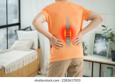 Lumbar intervertebral spine hernia, man with back pain at home, spinal disc disease, painful area highlighted in red - Shutterstock ID 2283617033