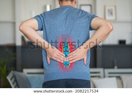 Lumbar intervertebral spine hernia, man with back pain at home, spinal disc disease, painful area highlighted in red