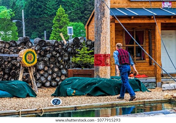 Lumber\
jack throwing axe at log target in tourist\
show.