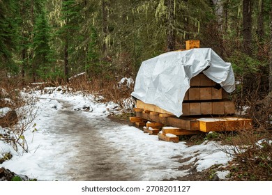 Lumber stack covered on a snowy forest path, awaiting its journey ahead. Emerald Lake, BC