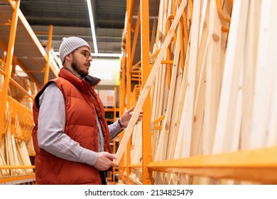 In A Lumber Store, A Man Chooses Wooden Blocks And Boards