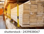 Lumber yard full rack of framing studs 2 by 6 pine spruce woods on elevated shelves, yellow painted gauge steel guard post prevents heavy pile construction material falling, hardware store safety. USA