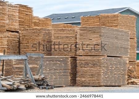 A lumber yard of a hardware store with bulk stacks of short-cut lumber, boards, and rough planks stockpiled for sale. The timber yard has sprucewood sawed for building materials and stacked for sale.