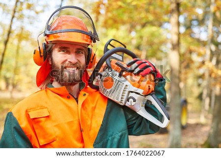 Lumberjack or forest worker with chainsaw and protective gear in the forest
