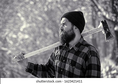 Lumberjack In The Woods With An Ax. Bearded Man In Hat With A Hatchet. Handsome Man, Hipster. Lumberjack Brutal Bearded Man With Beard And Moustache On Winter Day, Snowy Forest. Black And White.