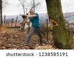 Lumberjack worker chopping down a tree breaking off many splinters in the forest with big axe.