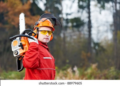 Lumberjack Worker In Protective Safety Work Wear With Chainsaw At Forest