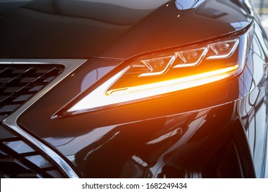 Luminous headlight on a new car in the showroom