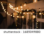 Luminous incandescent lamps hang in the form of a garland on wires, against the background of a shop window. Background from a garland. Incandescent lamps.