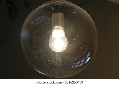 A Luminous Light Bulb In A Large Glass Lampshade