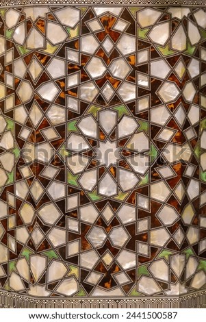 Luminous mother-of-pearl inlay with geometric design in a Turkish Islamic art piece, radiating luxury in warm and cool hues