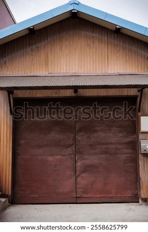 Lumpy rust brown colored doors adorn a warehouse featuring orange brown corrugated sheetmetal siding and a light blue roof, topping off a well coordinated color scheme for a small Japanese warehouse.