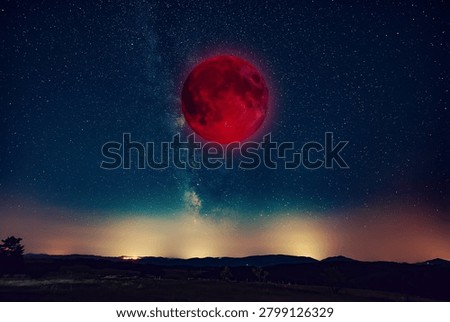 Lunar eclipse, stars and planets above landscape silhouettes.