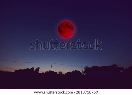 Lunar eclipse, stars and planets above landscape silhouettes.