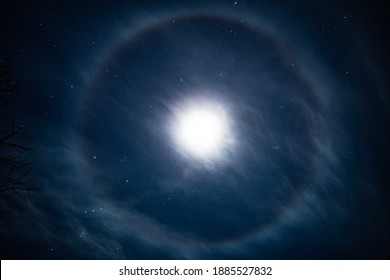 A lunar halo around the moon, showing multiple bands of color in its rainbow halo form, over East Hartland, CT, USA in early winter. This long exposure also shows the constellation Orion and others
