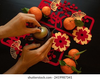 Lunar New year flat-lay with hands , oranges, pot and Chinese wishes characters 