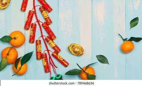 Lunar new year.Firecrackers and Chinese gold ingots and Traditional Red envelopes and decoration with Fresh oranges on wooden background